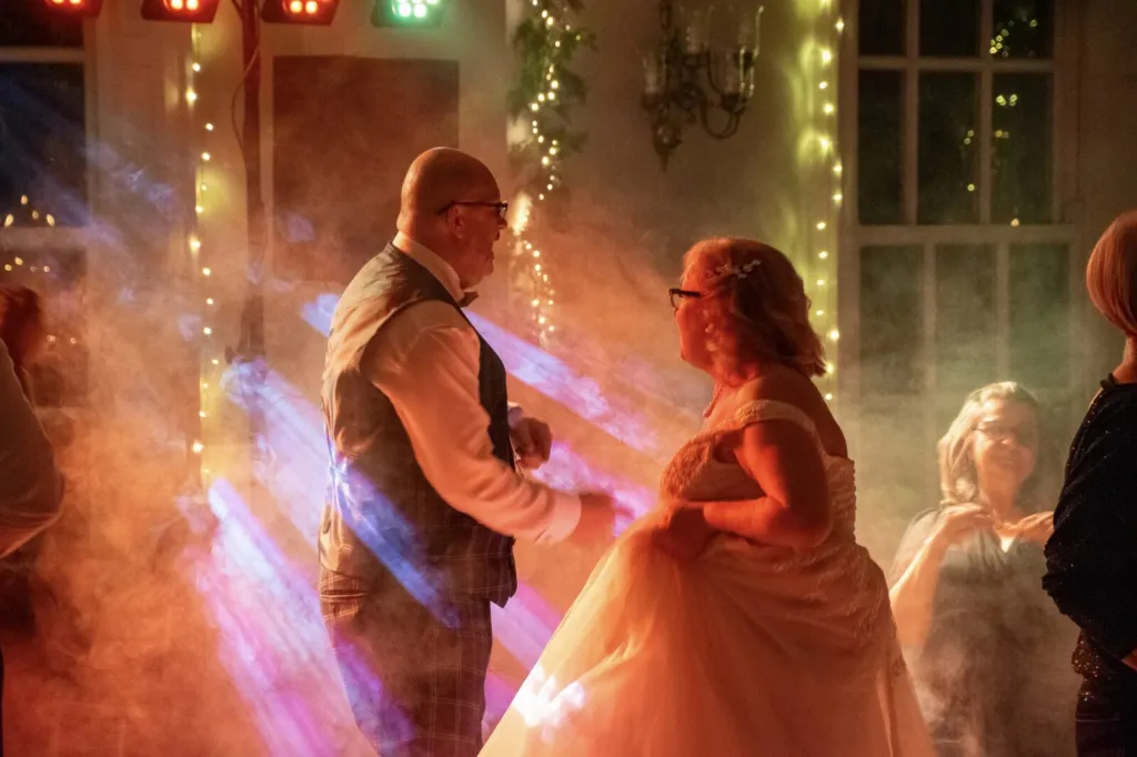 Couple dancing on a hazy dance floor with coloured light beams