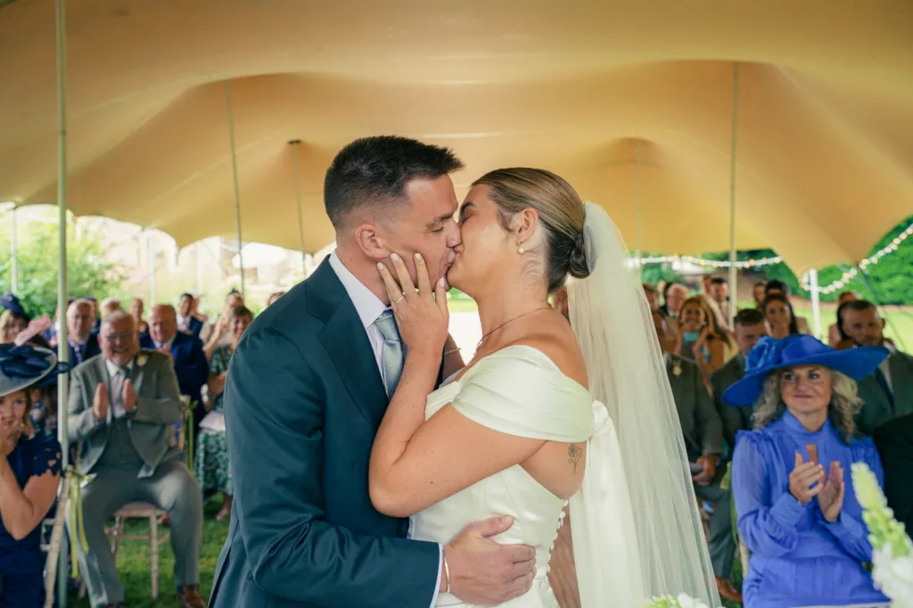 The kiss under the stretch tent, with the guests applauding