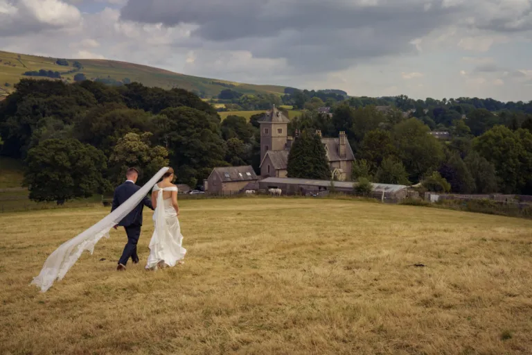 A couple walking across a meadow towards a stone tower