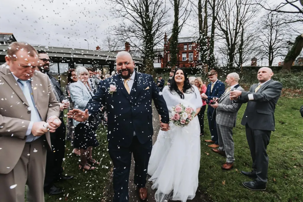 Newlyweds walking a garden path through a confetti shower with guests on both sides